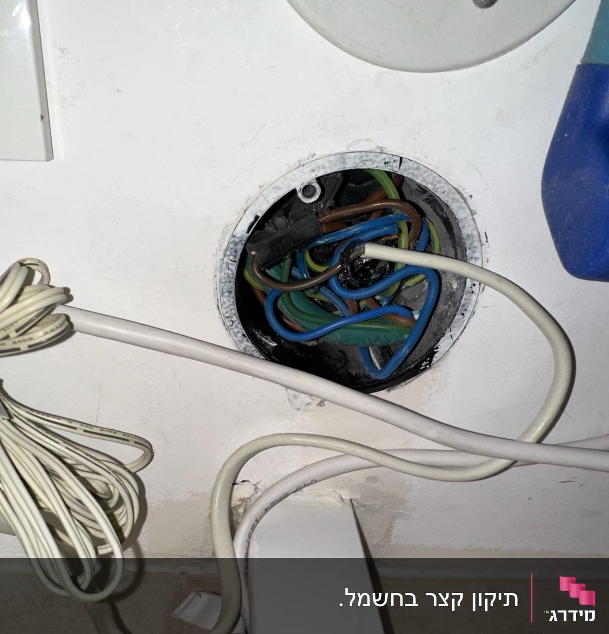 חוטי חשמל צבעוניים יוצאים מקופסת חיבורים בקיר